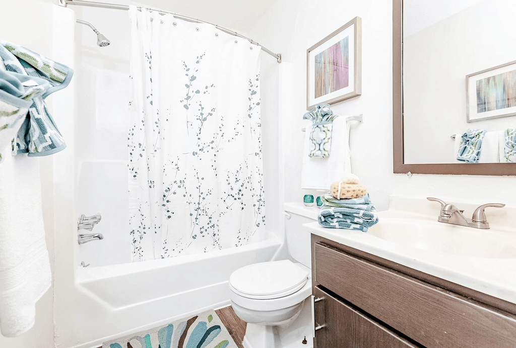 A white toilet sits next to a shower curtain in a bathroom at Regency Park Apartment Homes, Raleigh, 27616