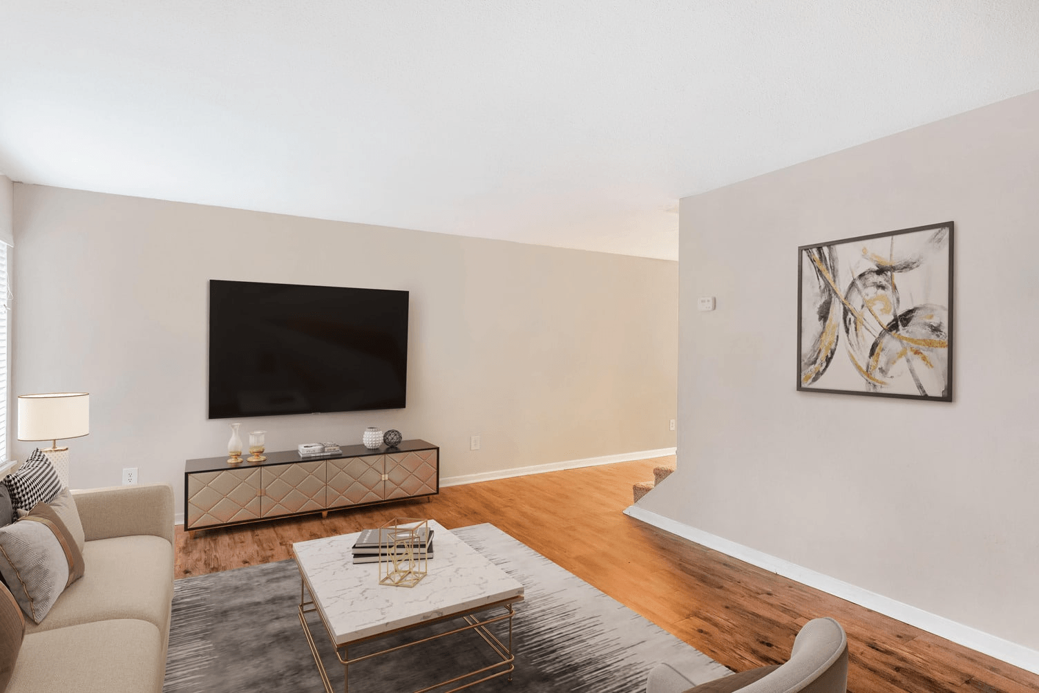 A living room with a couch, coffee table, and a painting on the wall.