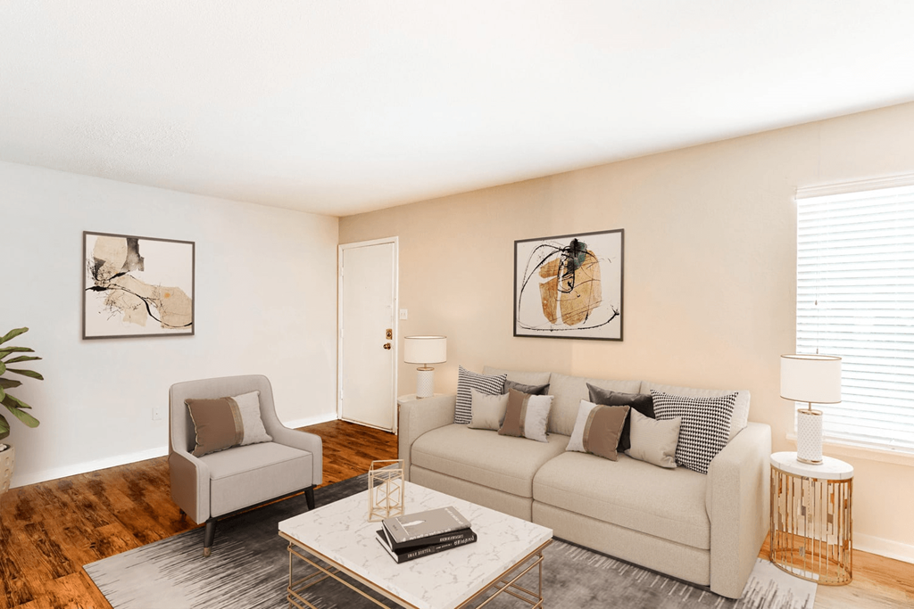 A living room with a couch, chair, and two pictures on the wall at Regency Park Apartment Homes, Raleigh