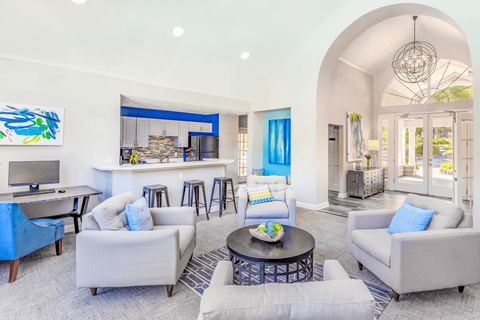 A living room with a blue couch and a painting on the wall.