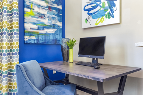 A blue chair sits in front of a desk with a computer on it.