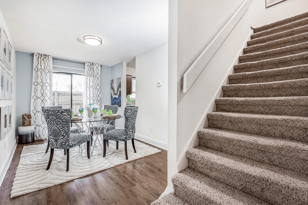 A staircase with a carpeted runner and a dining area with chairs and a table at Regency Park Apartment Homes, Raleigh, 27616