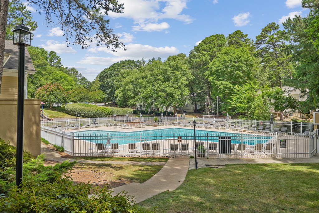 A large outdoor swimming pool surrounded by trees and a fence at Regency Park Apartment Homes, North Carolina, 27616