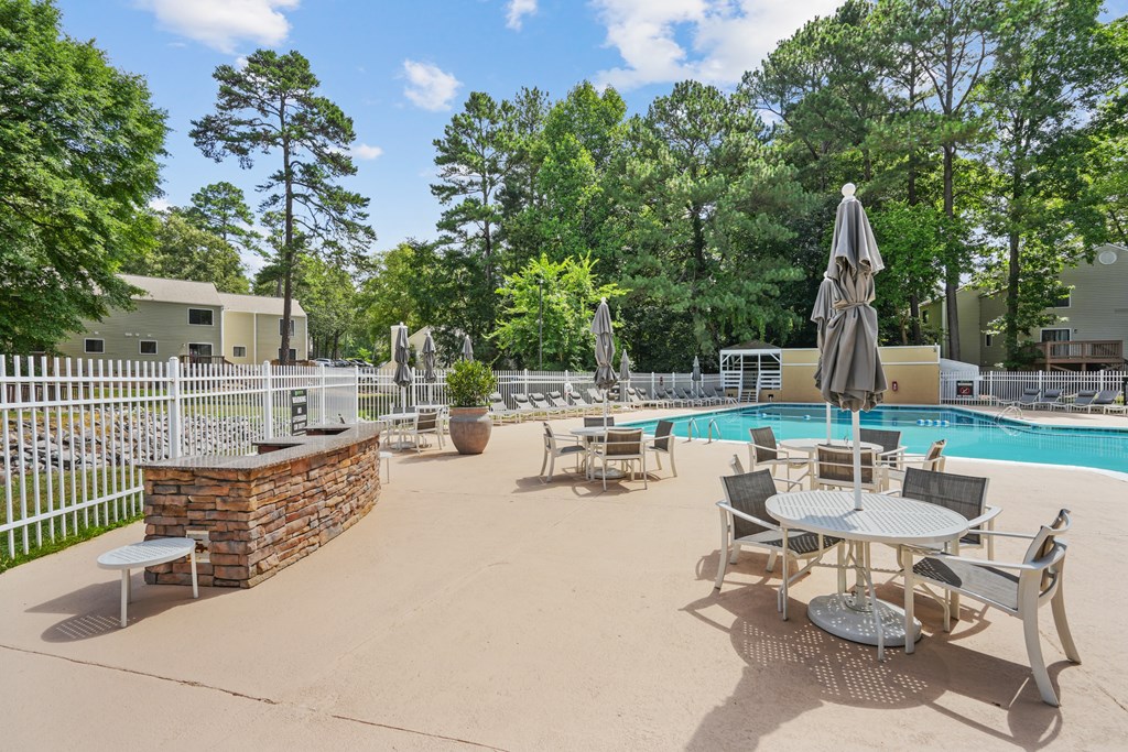 A pool area with a table and chairs and a fence at Regency Park Apartment Homes, North Carolina, 27616