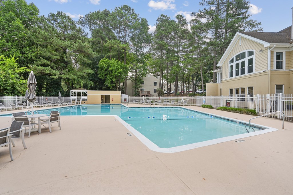 A large outdoor swimming pool surrounded by a fence and trees at Regency Park Apartment Homes, Raleigh, NC, 27616