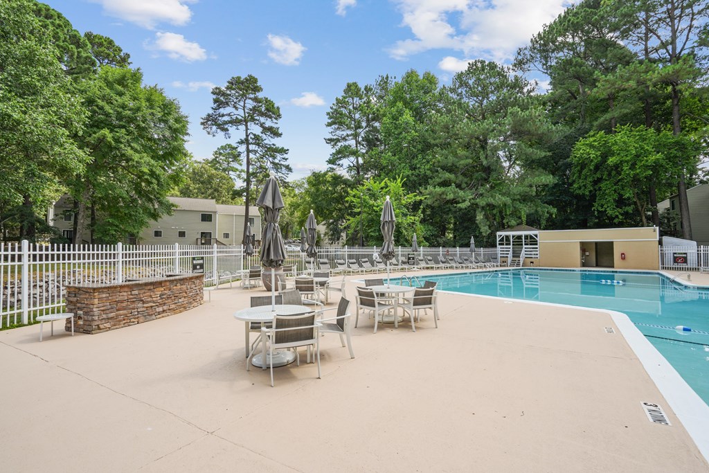 A pool area with a table and chairs and a fence at Regency Park Apartment Homes, Raleigh