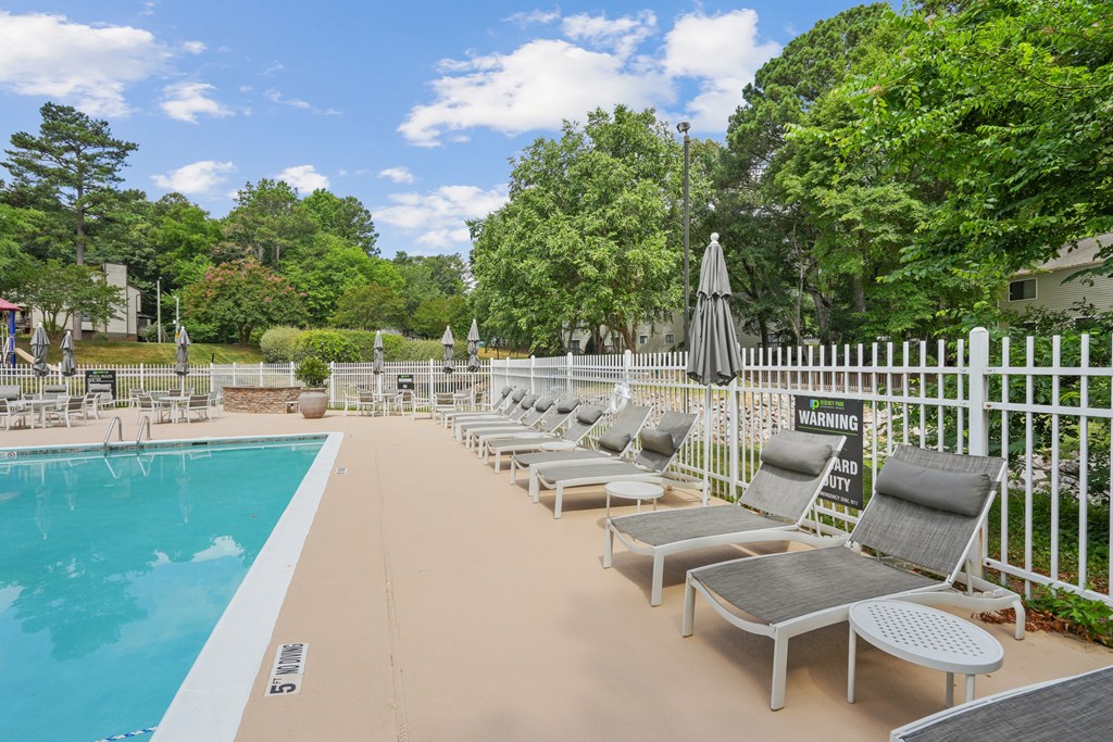 A pool area with sun loungers and a warning sign at Regency Park Apartment Homes, Raleigh, NC
