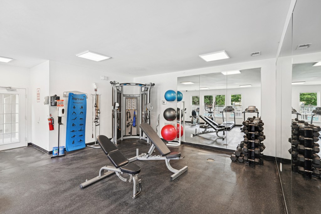 A gym with a variety of equipment including weights and a bench at Regency Park Apartment Homes, Raleigh, NC, 27616