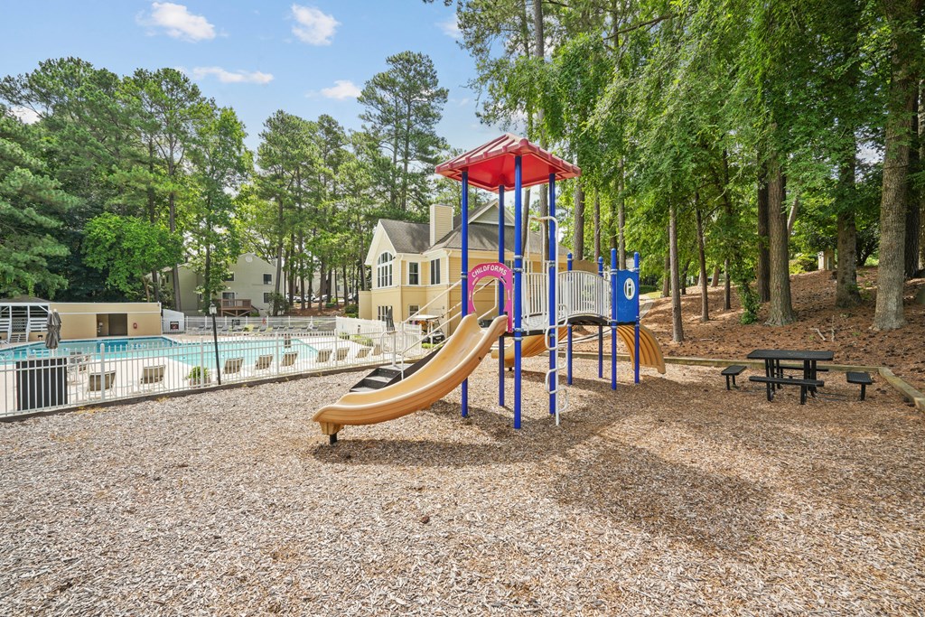 A playground with a yellow slide and a red and blue structure at Regency Park Apartment Homes, North Carolina