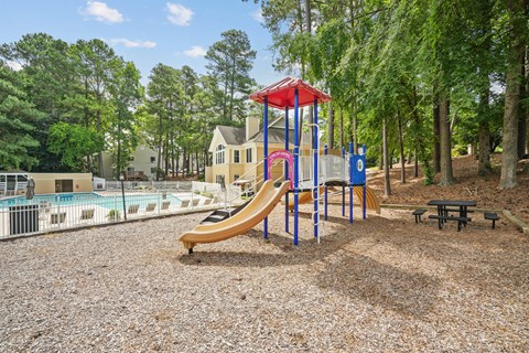 A playground with a yellow slide and a red and blue structure.