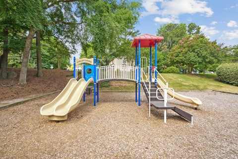 A playground with a yellow slide and a blue and white structure.