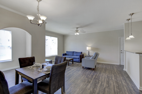 A dining room with a table set for two and a couch in the background.