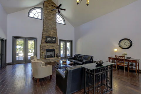 A living room with a stone fireplace and a clock on the wall.