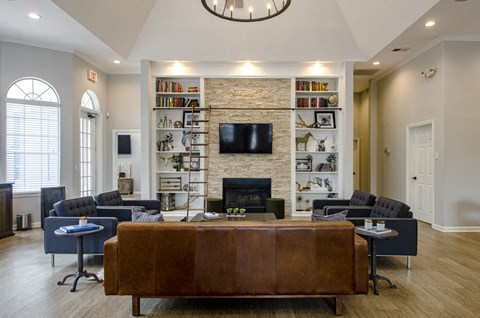 A living room with a brown leather couch and a stone fireplace.