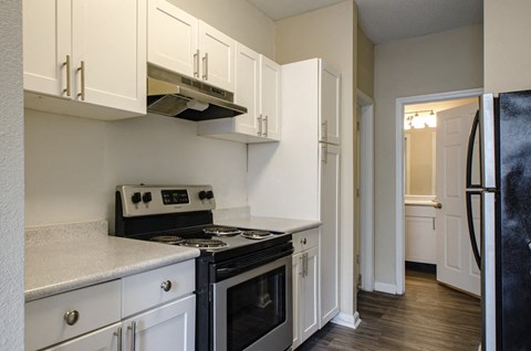 A kitchen with white cabinets and black appliances.