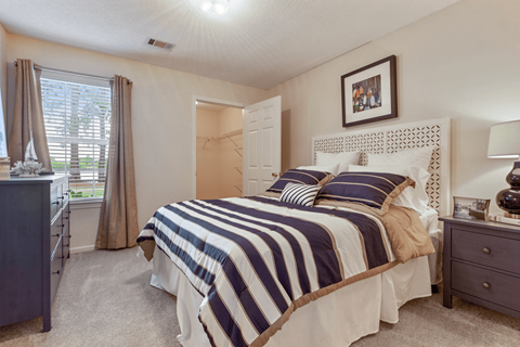A bedroom with a bed, nightstand, and window.