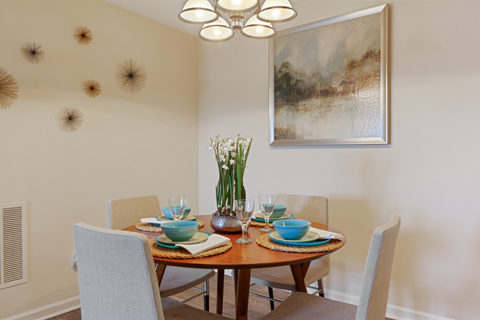 a dining room with a table and chairs and a painting on the wall