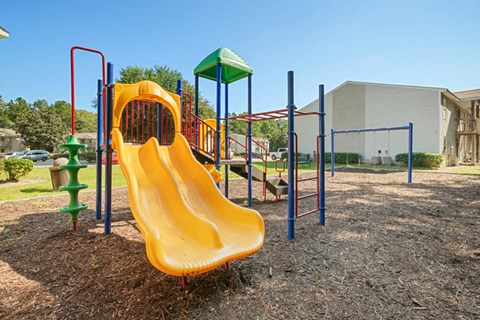 a mulched playground with a yellow slide
