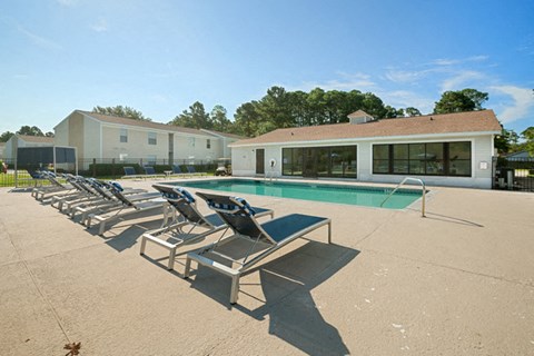 A pool with sun loungers and a building in the background.