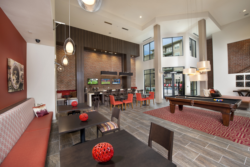 Resident lounge area facing multiple seating areas, a pool table, and the exterior door that leads to the pool