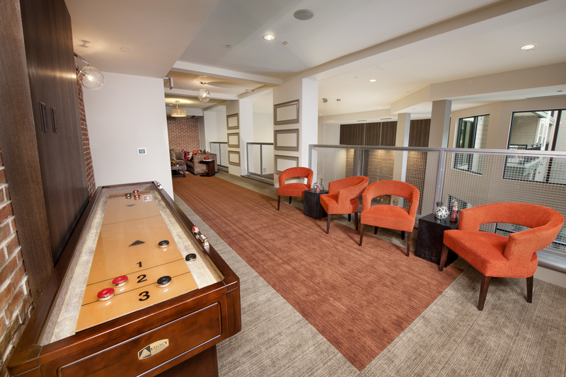 Upper level of resident clubhouse facing a shuffle board table and two sitting areas.