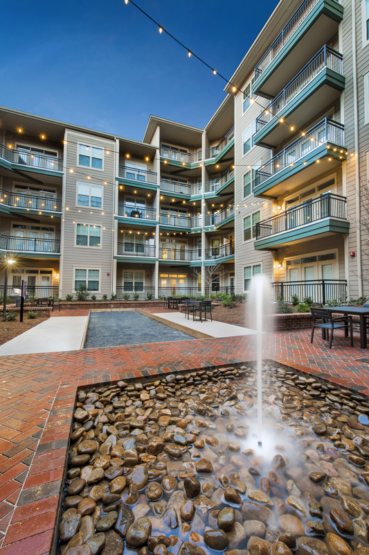 Exterior courtyard facing a fountain and hot tub, with many sitting tables.