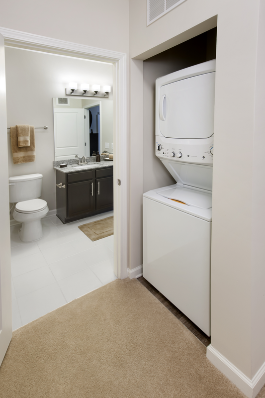 Apartment hallway facing stackable washer and dryer and looking into the bathroom