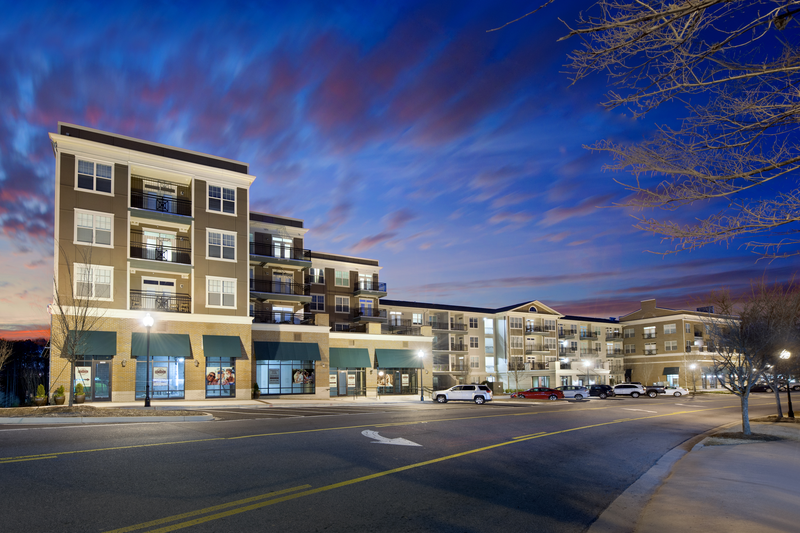 Nighttime view of retail space and exterior of the apartment building