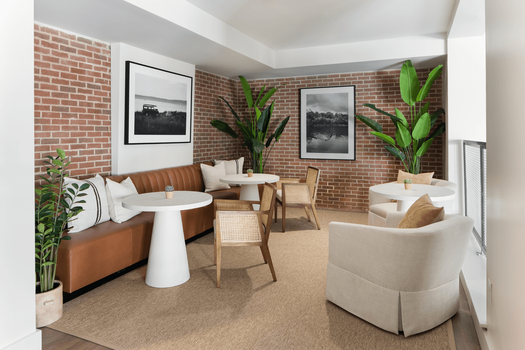 a living room with couches and chairs and a brick wall