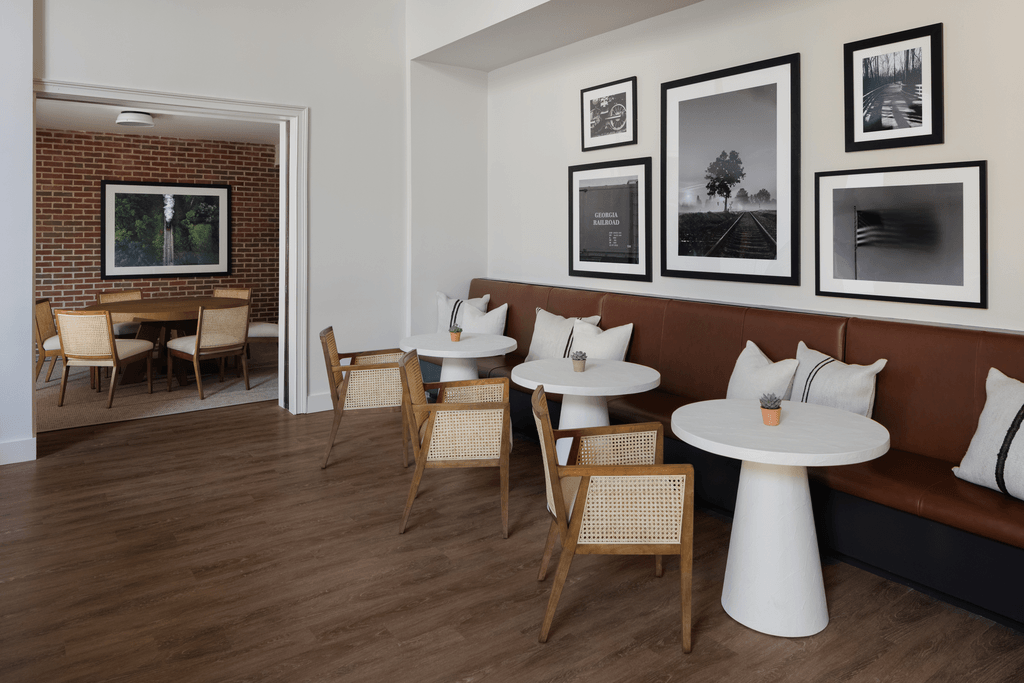 a seating area with tables and chairs in a room with a brick wall and pictures