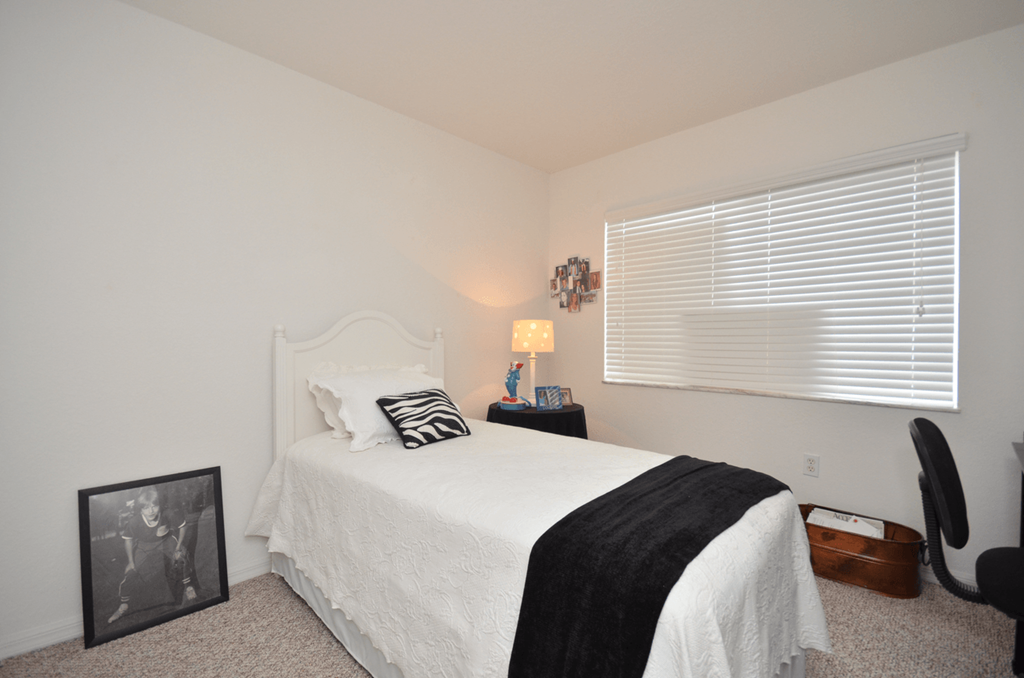 a bedroom with white walls and a white bed with a black and white pillow
