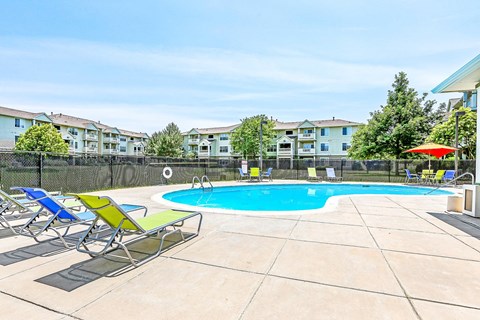 Community pool with colorful loungers and patio furniture at Riverwalk Apartments, Colorado