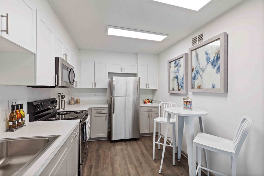 A kitchen with white cabinets and a refrigerator.