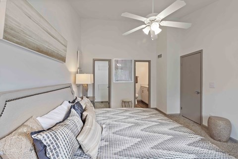 A bedroom with a large bed and a ceiling fan.
