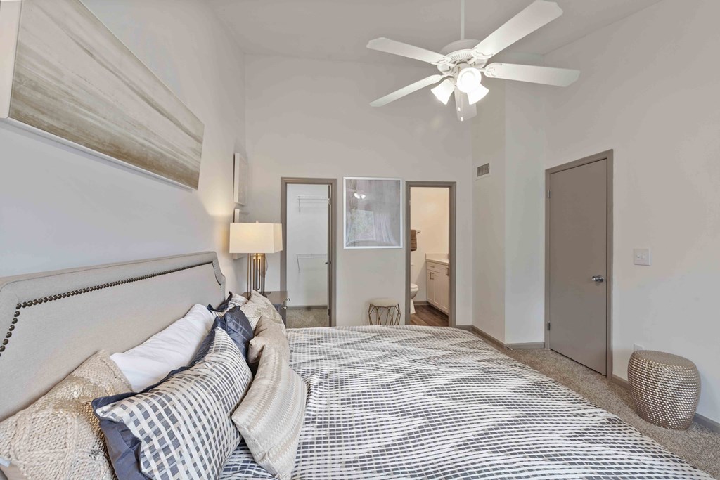 A bedroom with a large bed and a ceiling fan.