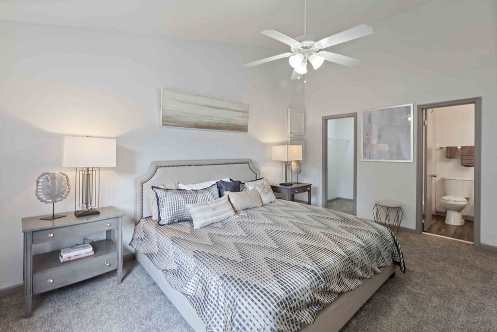 A bedroom with a large bed and a ceiling fan.