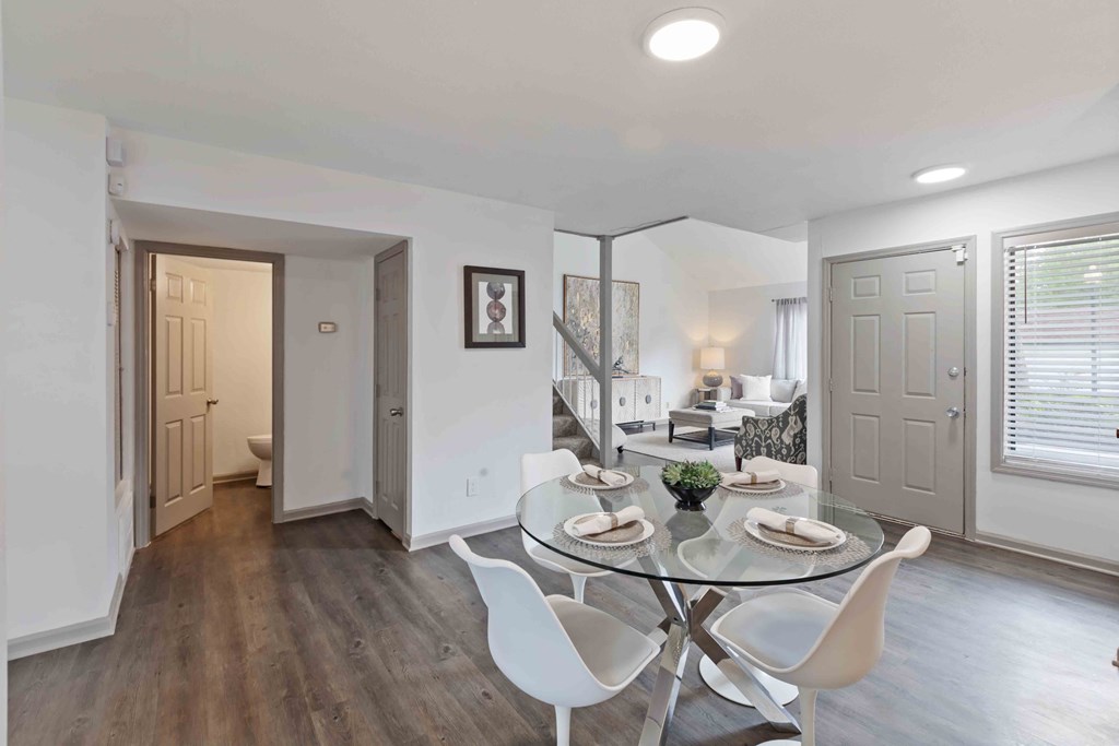 A dining room with a glass table and white chairs.