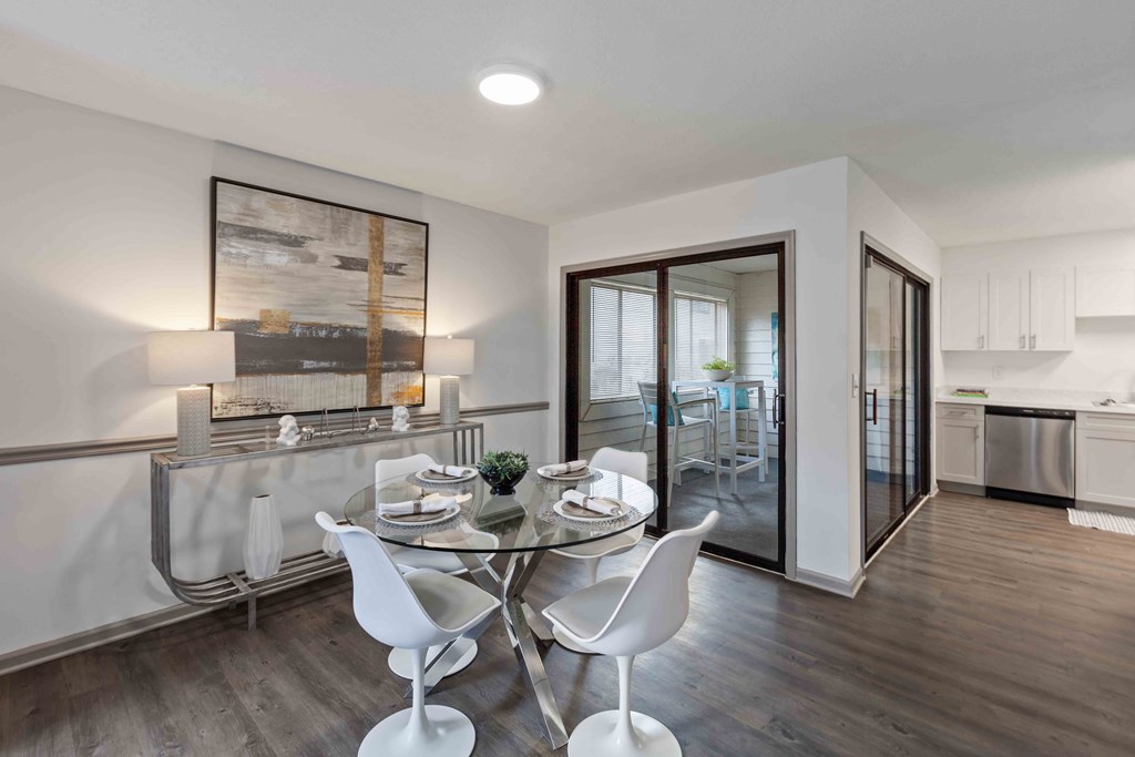 A modern dining room with a glass table and white chairs.