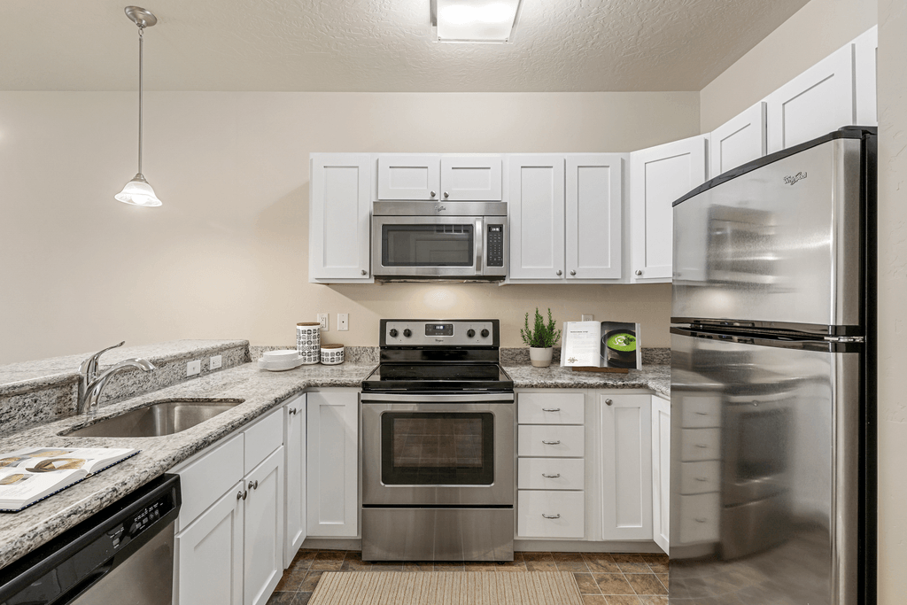 an empty kitchen with stainless steel appliances and white cabinets