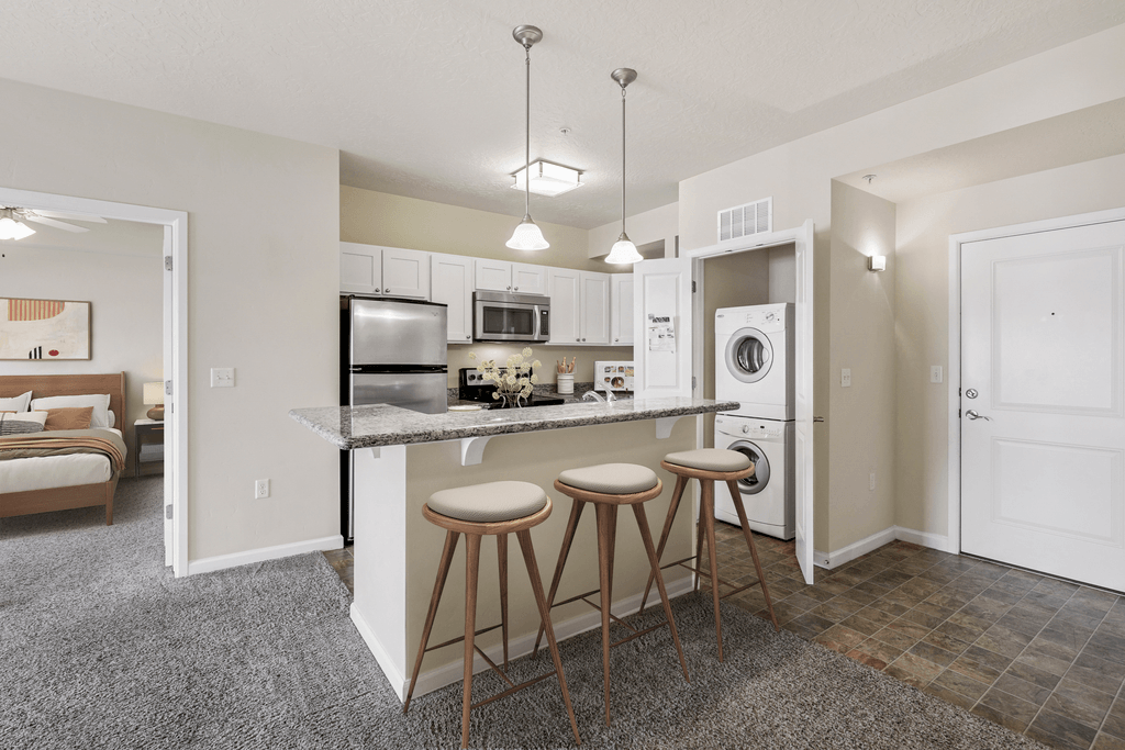 a kitchen with a bar and stools and a refrigerator