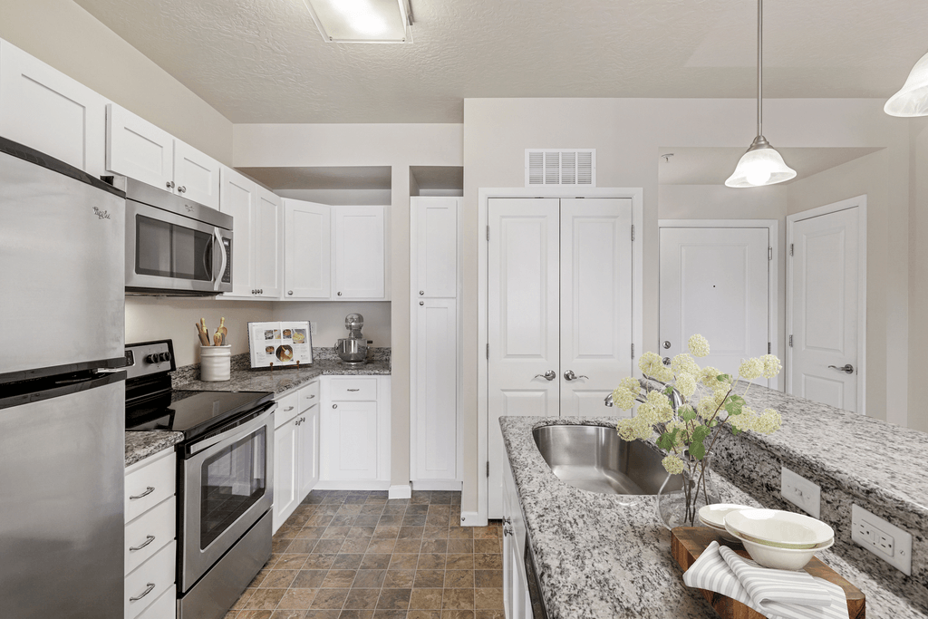 a white kitchen with marble counter tops and stainless steel appliances