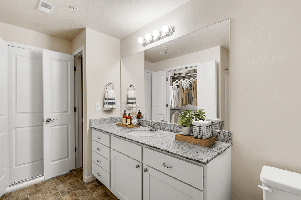 a bathroom with white cabinets and a sink and a mirror
