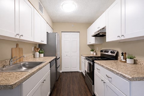 A kitchen with white cabinets and a granite countertop.
