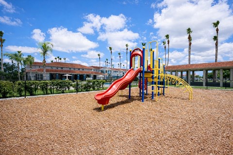 A playground with a red slide and yellow and blue play structures.