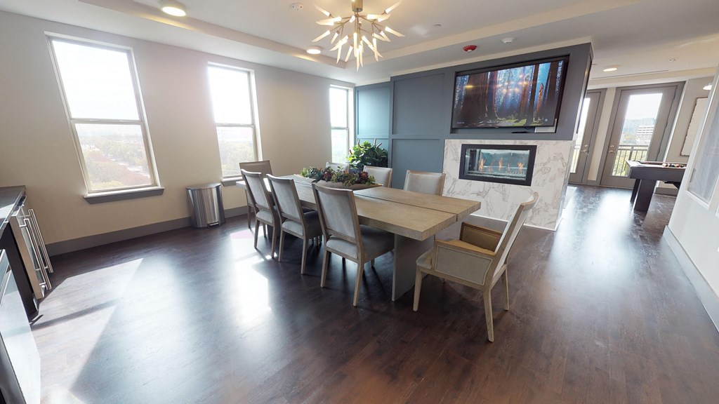 Resident sky lounge facing a table and sitting area complete with a television and fireplace.