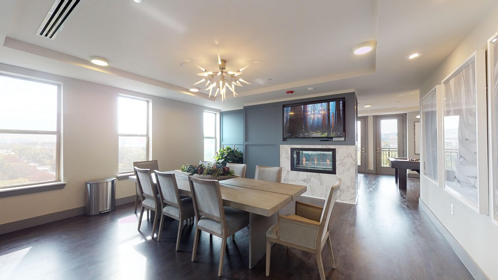 Resident sky lounge facing a table and sitting area complete with a television and fireplace.
