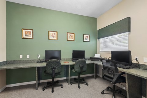 A room with green walls and a desk with two chairs and two computers.