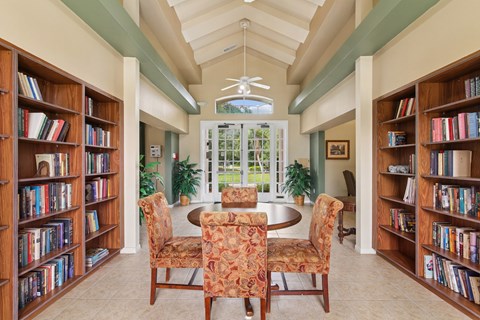A room with a table surrounded by chairs and bookshelves on both sides.