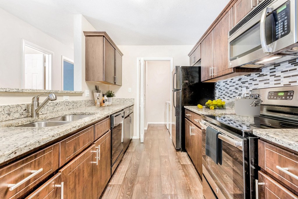A kitchen with wooden cabinets and a black stove top oven. at Southpark Commons Apartment Homes, Charlotte