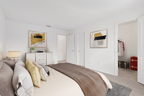 A bedroom with a large bed and two framed pictures on the wall.